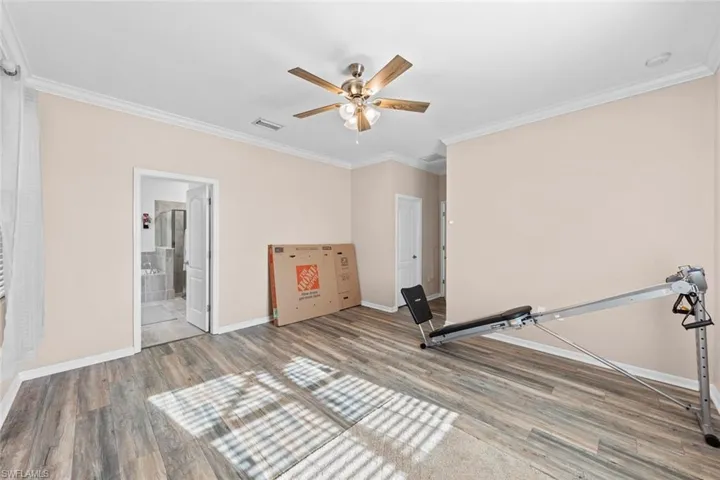 Exercise room featuring ceiling fan, ornamental molding, and hardwood / wood-style floors