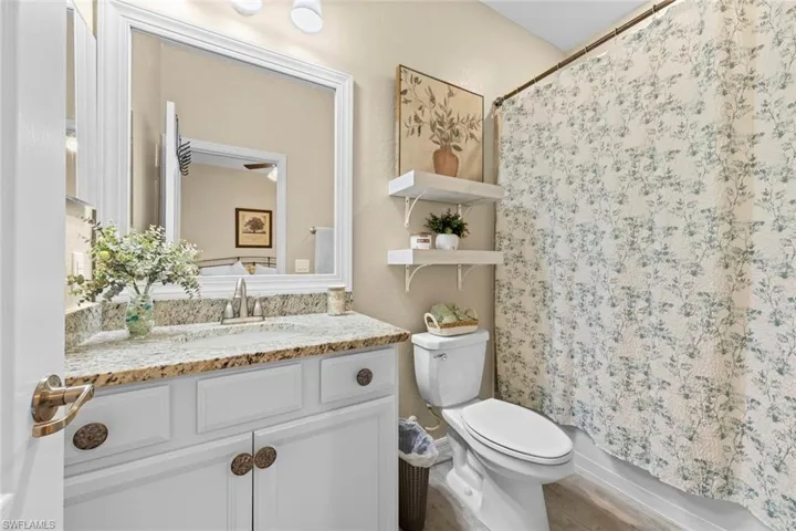 Full bathroom featuring wood-type flooring, shower / bath combination with curtain, vanity, and toilet