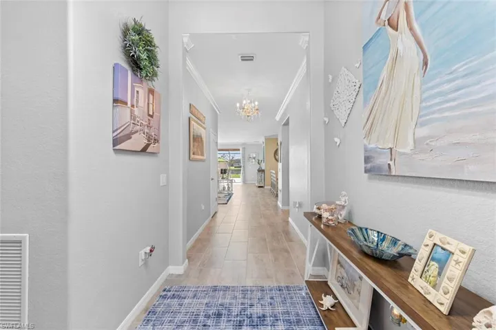 Corridor with light hardwood / wood-style flooring, crown molding, and a chandelier