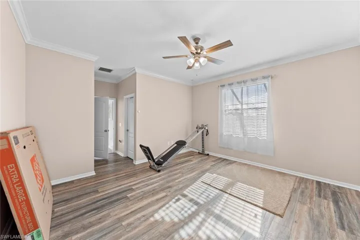 Workout area featuring ceiling fan, crown molding, and dark wood-type flooring