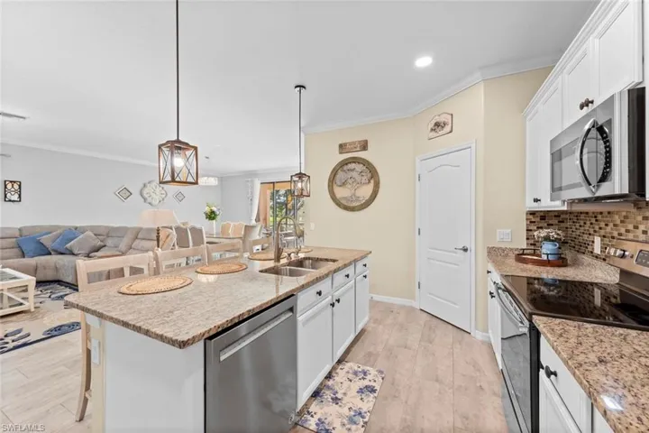 Kitchen featuring a kitchen island with sink, a breakfast bar, sink, appliances with stainless steel finishes, and white cabinetry
