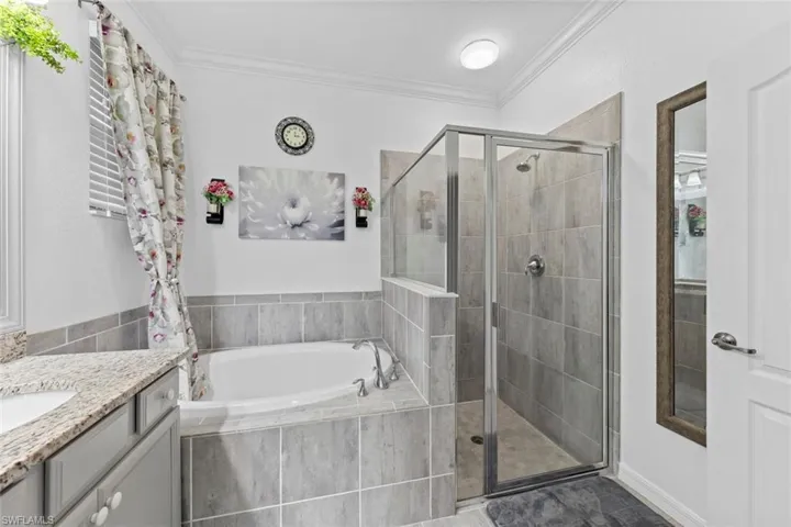 Bathroom with ornamental molding, vanity, and plus walk in shower