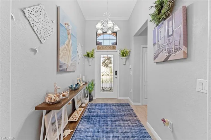 Foyer entrance with ornamental molding, hardwood / wood-style floors, and a chandelier