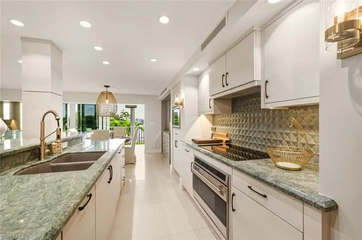 Kitchen with stainless steel oven, recessed lighting, light stone countertops, decorative light fixtures, and tasteful backsplash