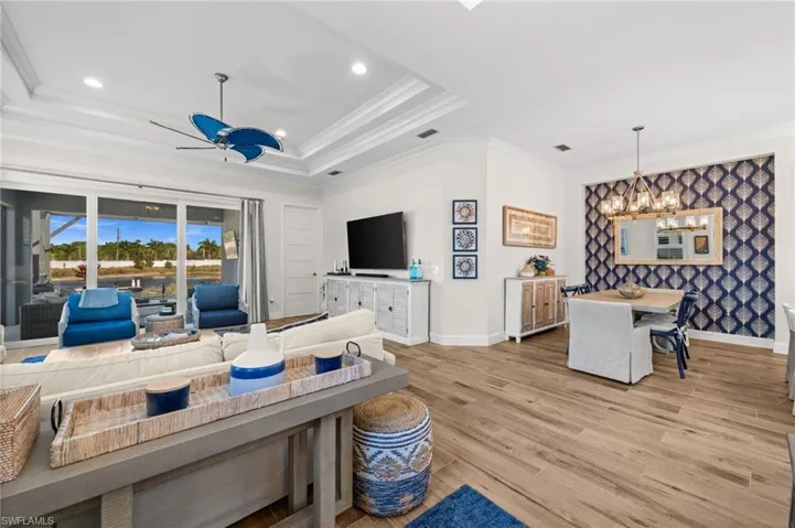 Living area featuring light wood finished floors, a ceiling fan, ornamental molding, and a chandelier