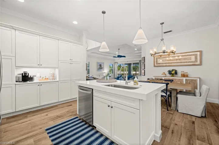 Kitchen featuring an island with sink, crown molding, white cabinets, light wood finished floors, and ceiling fan