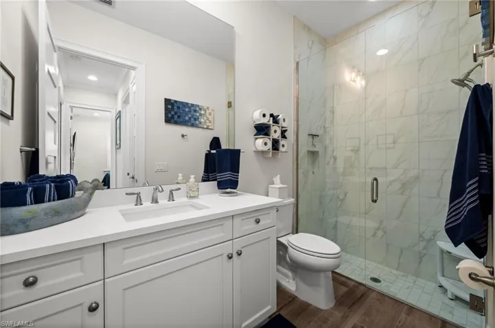 Full bath featuring vanity, a stall shower, dark wood finished floors, and recessed lighting