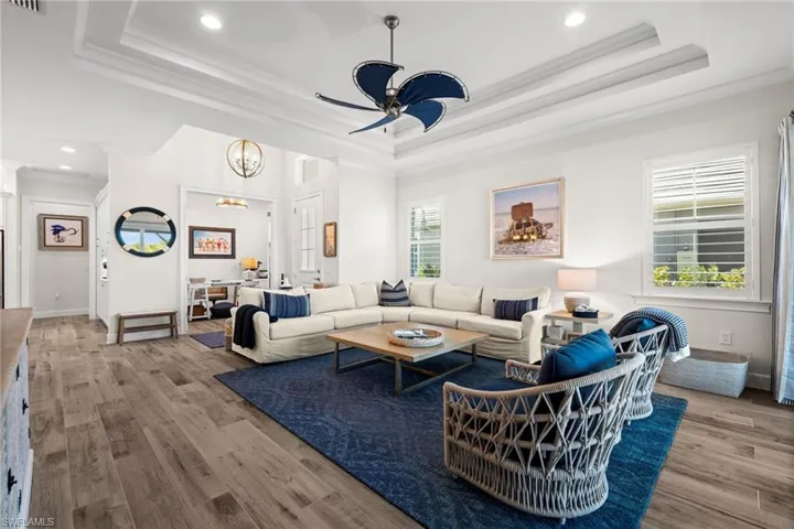 Living room with light wood finished floors, a ceiling fan, recessed lighting, and ornamental molding
