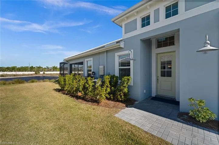 Property entrance featuring stucco siding, a yard, and a sunroom