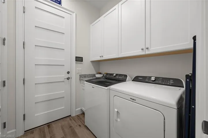 Laundry room featuring light wood-style floors, washer and dryer, and cabinet space