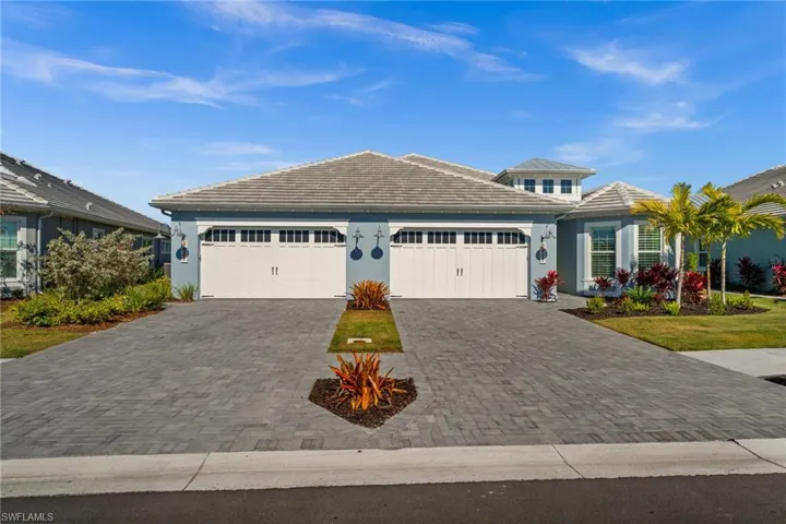 View of front facade with a tile roof, decorative driveway, stucco siding, and a garage