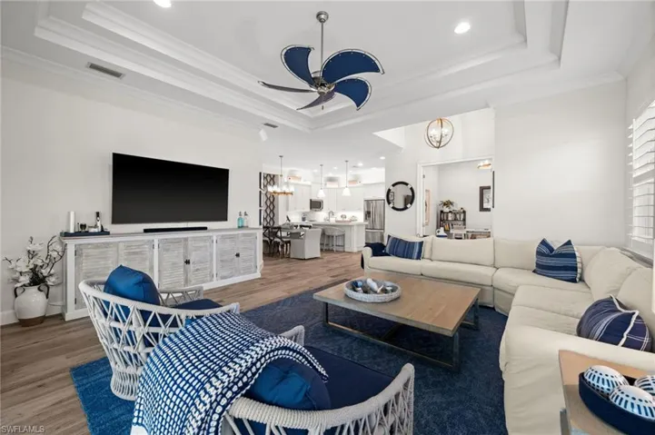 Living area featuring hanging lights, ceiling fan, wood finished floors, and crown molding