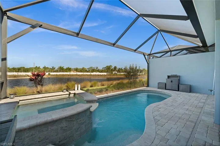 Integrated pool / hot tub featuring a sunroom, glass enclosure, a patio, and a water view
