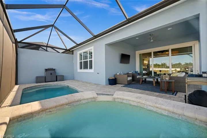 Outdoor pool with a sunroom, a patio area, glass enclosure, and an outdoor hangout area