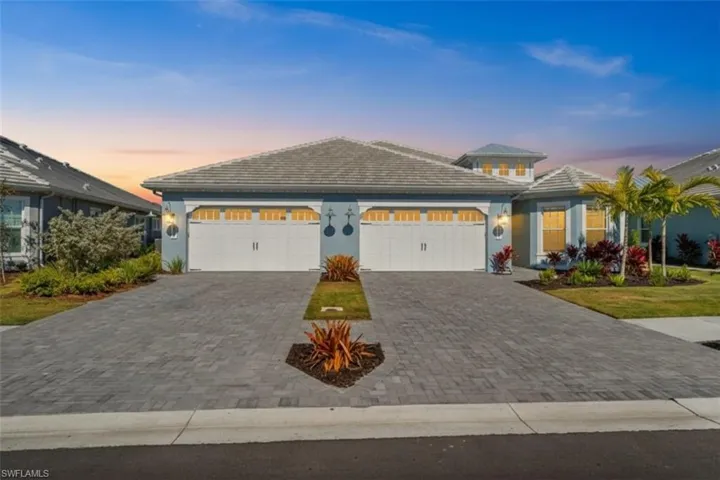 View of front of property featuring decorative driveway, stucco siding, and an attached garage
