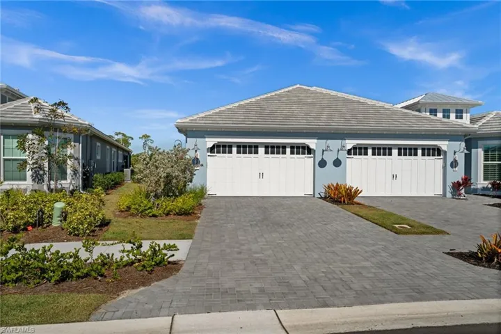 View of front facade featuring decorative driveway, a tiled roof, and stucco siding