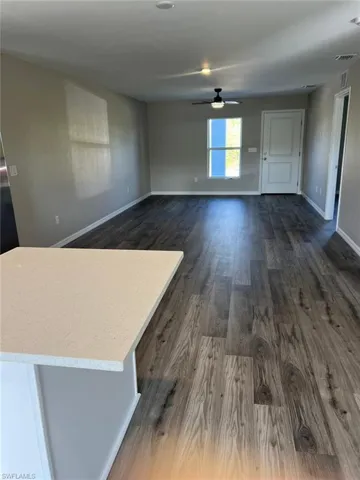 Unfurnished living room featuring dark wood-type flooring and ceiling fan