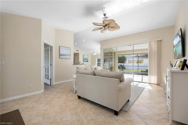 Living room with ceiling fan, vaulted ceiling, and light tile patterned floors