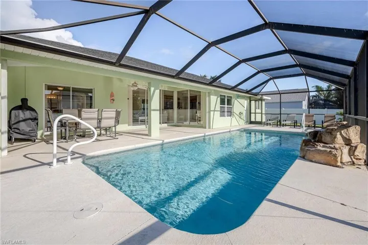 View of pool with a patio, glass enclosure, and ceiling fan