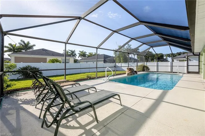View of swimming pool featuring a patio, a yard, and glass enclosure