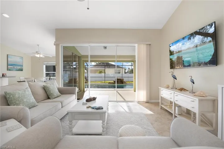 Living room with lofted ceiling, light tile patterned floors, and ceiling fan