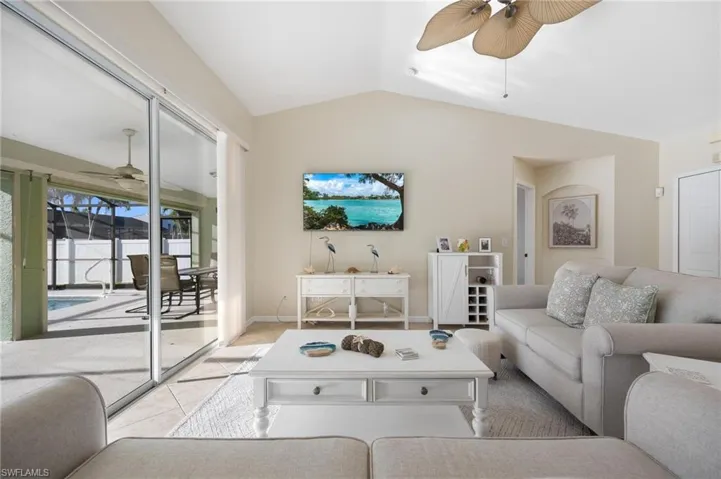 Tiled living room with ceiling fan and lofted ceiling