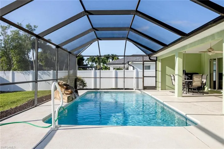 View of pool with a patio, ceiling fan, and glass enclosure