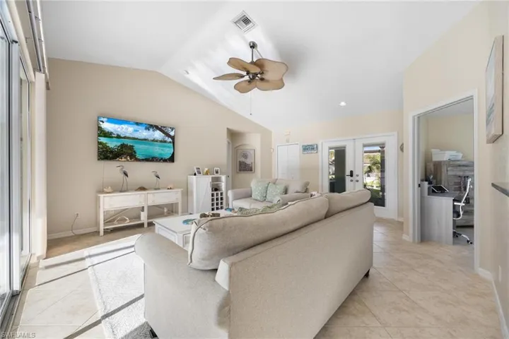 Living room with vaulted ceiling, french doors, light tile patterned floors, and ceiling fan