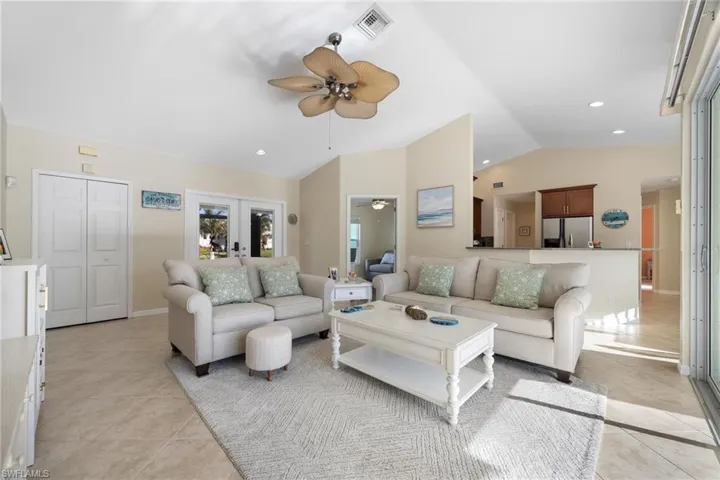 Living room with lofted ceiling, french doors, light tile patterned floors, and ceiling fan