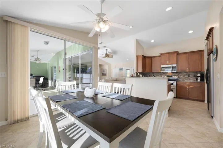 Dining area with ceiling fan, vaulted ceiling, and light tile patterned floors