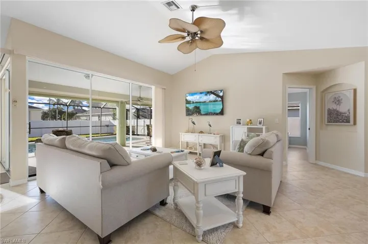 Tiled living room with ceiling fan and lofted ceiling