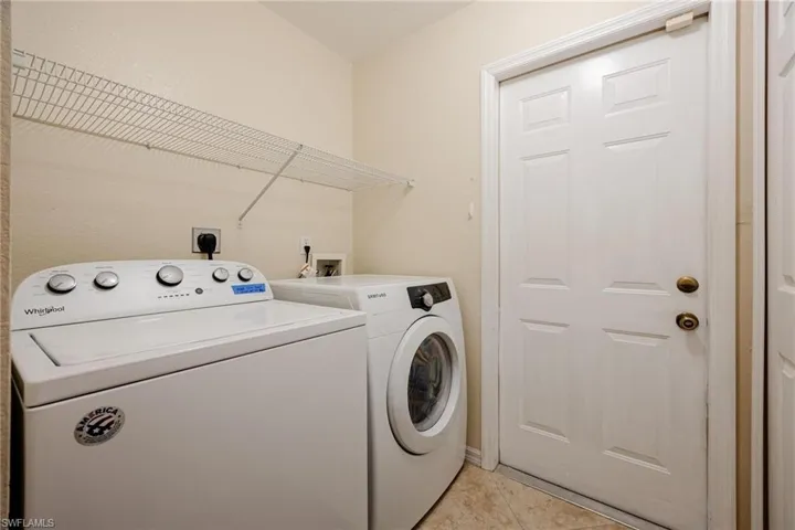 Washroom with light tile patterned flooring and washing machine and dryer
