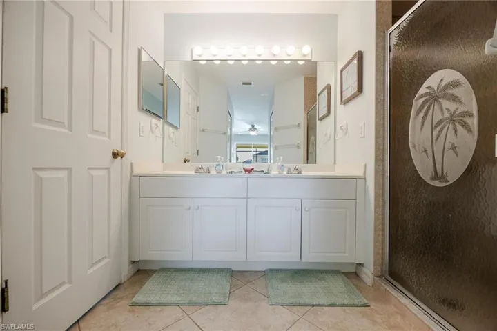 Bathroom featuring a shower with shower door, double vanity, and tile patterned floors