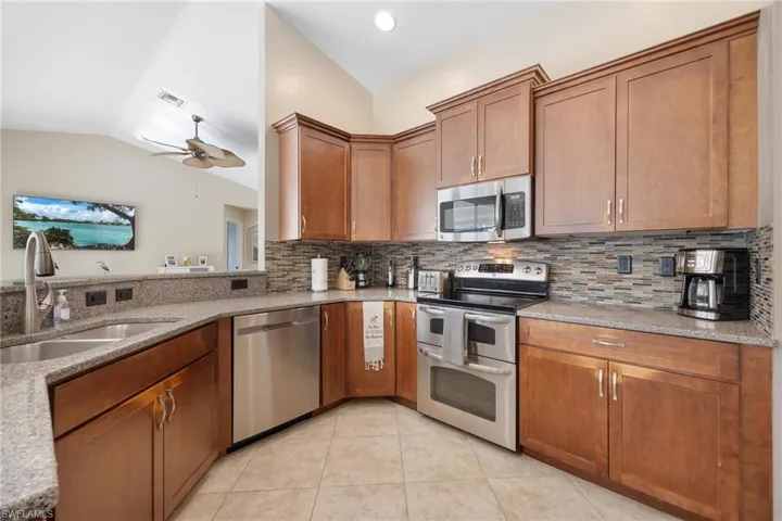 Kitchen with decorative backsplash, ceiling fan, vaulted ceiling, and stainless steel appliances