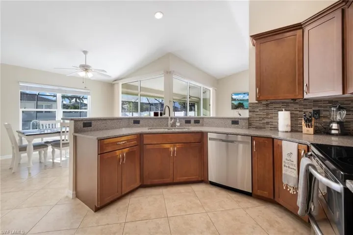 Kitchen with appliances with stainless steel finishes, sink, kitchen peninsula, light tile patterned floors, and ceiling fan