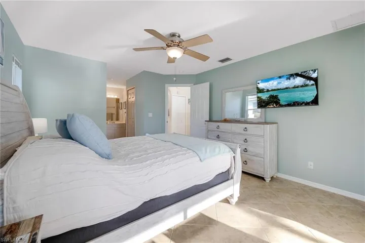 Bedroom with ensuite bath, ceiling fan, and light tile patterned floors