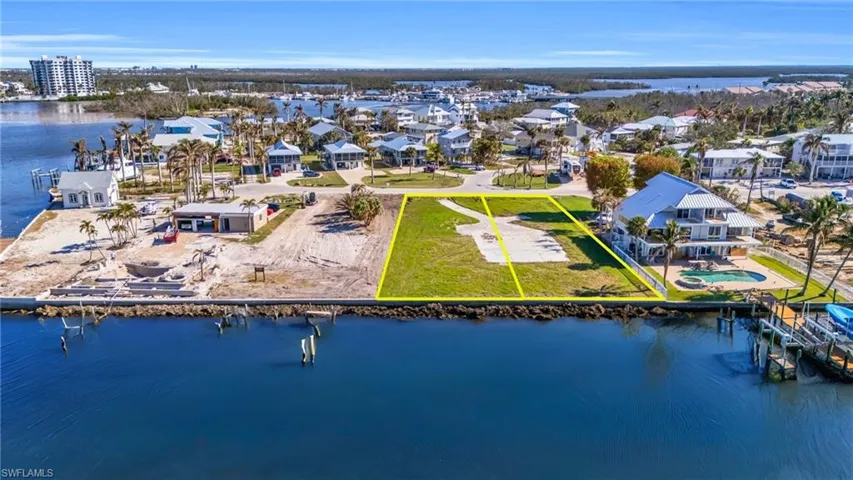Aerial view of residential area featuring a large body of water and property parcel outlined - Virtually Edited Image