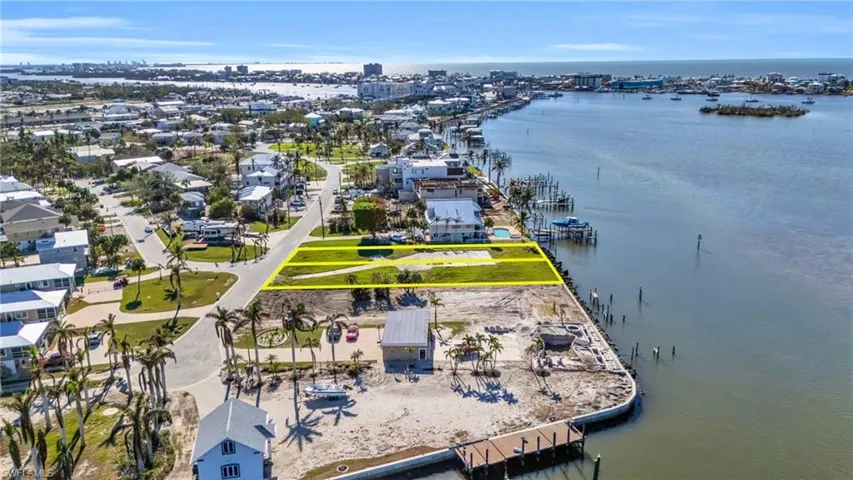 Aerial perspective of suburban area featuring a large body of water and property boundaries highlighted - Virtually Edited Image