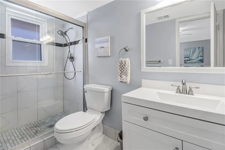 Bathroom featuring vanity with extensive cabinet space, an enclosed shower, toilet, and tile floors