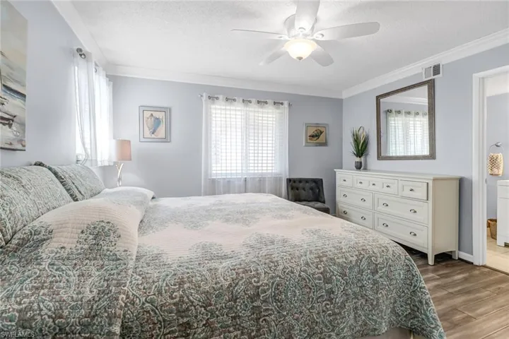 Bedroom featuring ceiling fan, a textured ceiling, ornamental molding, and wood-type flooring