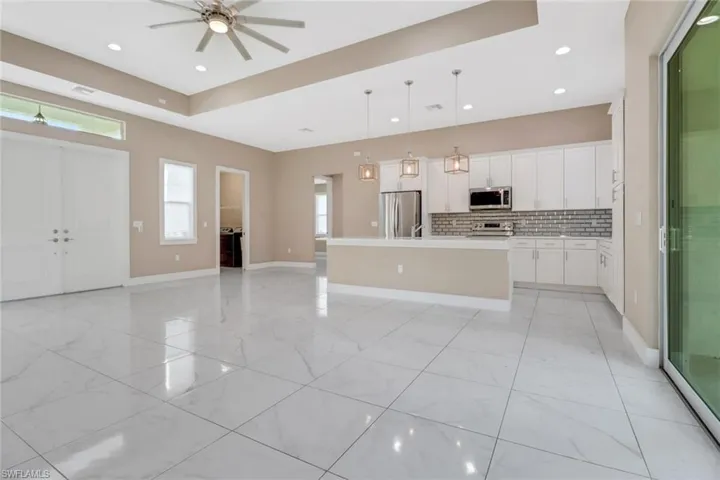 Kitchen with decorative backsplash, stainless steel appliances, a kitchen island, upgraded pendant lighting, and white cabinetry