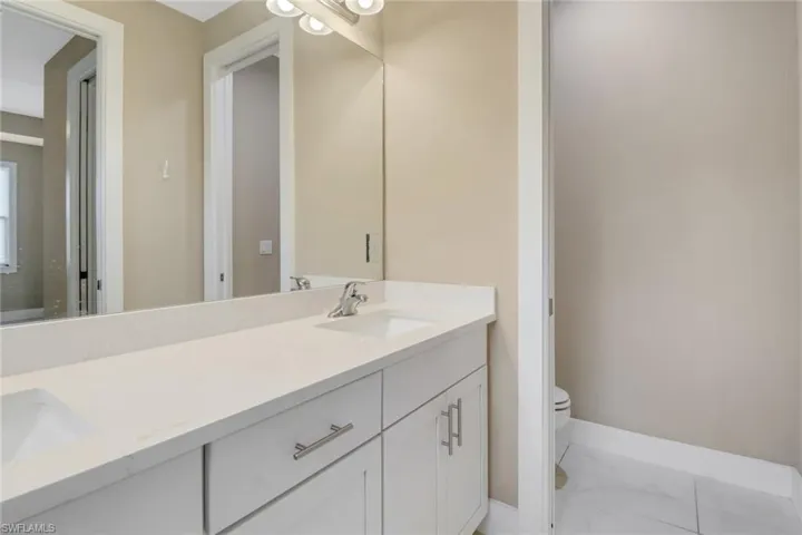 Primary bathroom with upgraded countertops, white Shaker cabinetry and private water closet