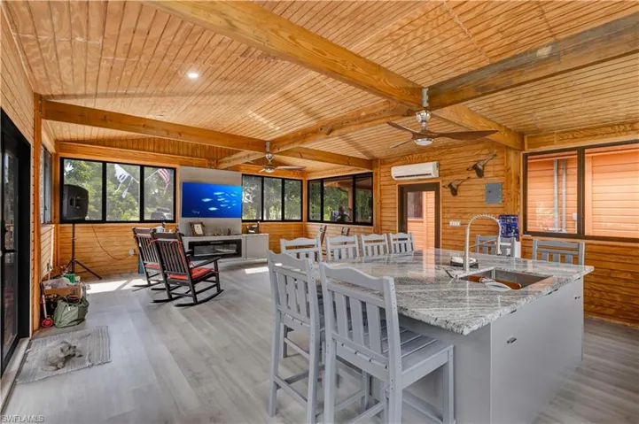 Kitchen featuring wooden walls, a ceiling fan, a wood ceiling with exposed beams, light wood finished floors, and gray cabinets