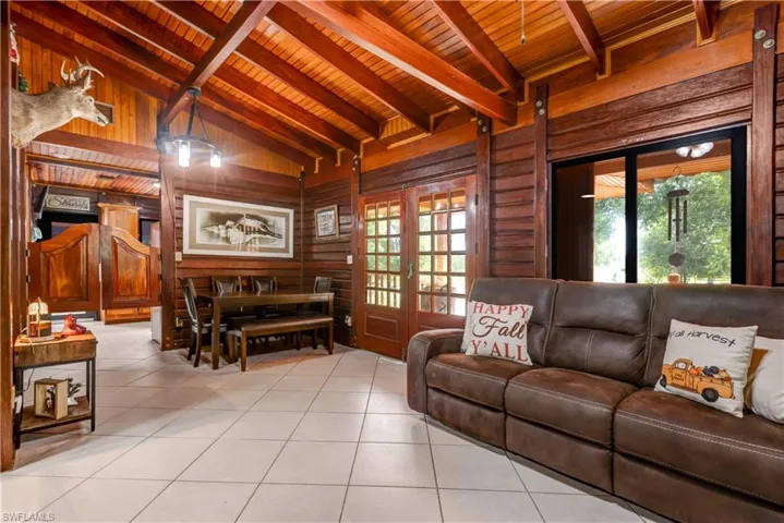 Living area featuring light tile patterned floors, french doors, wooden ceiling, and wooden walls