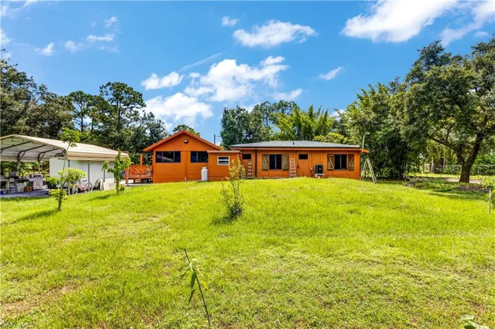 Back of property with a yard and a detached carport