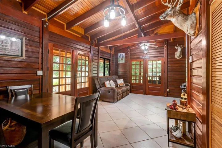 Dining space with french doors, wood ceiling, light tile patterned flooring, a ceiling fan, and wood walls