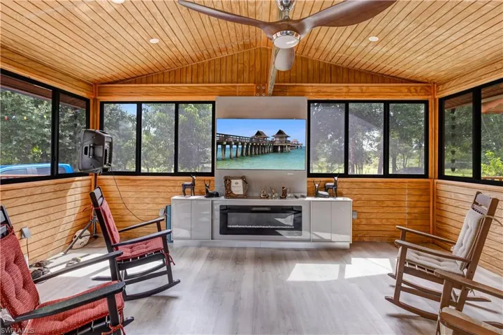 Sunroom with wood walls, plenty of natural light, vaulted ceiling, wood ceiling, and wood finished floors
