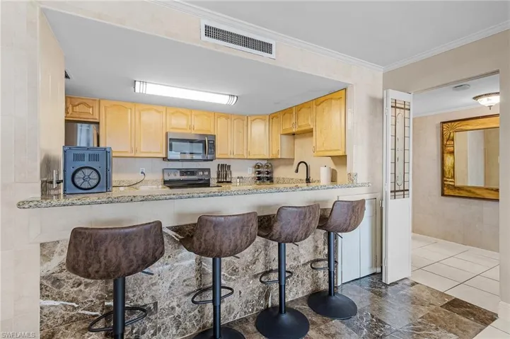 Kitchen with visible vents, a sink, light brown cabinetry, crown molding, and stainless steel appliances