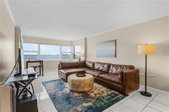 Living area with crown molding, light tile patterned floors, baseboards, and a water view