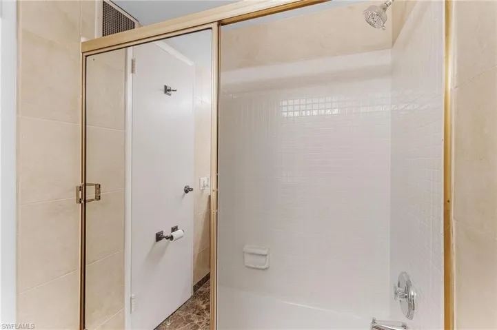 Bathroom featuring bath / shower combo with glass door